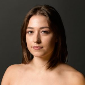 Lucy Pierson headshot. Dark haired woman with brown eyes and a septum ring.