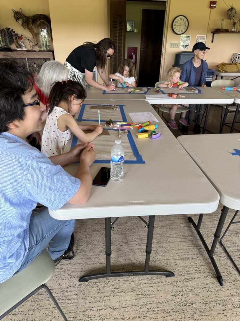 children drawing at long plastic tables