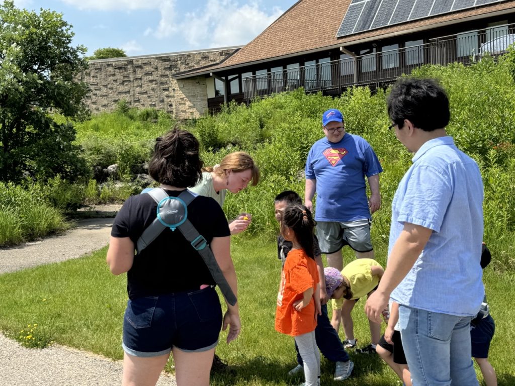 Kohler fellow showing children and adults a specimen in front of the UW arboretum building
